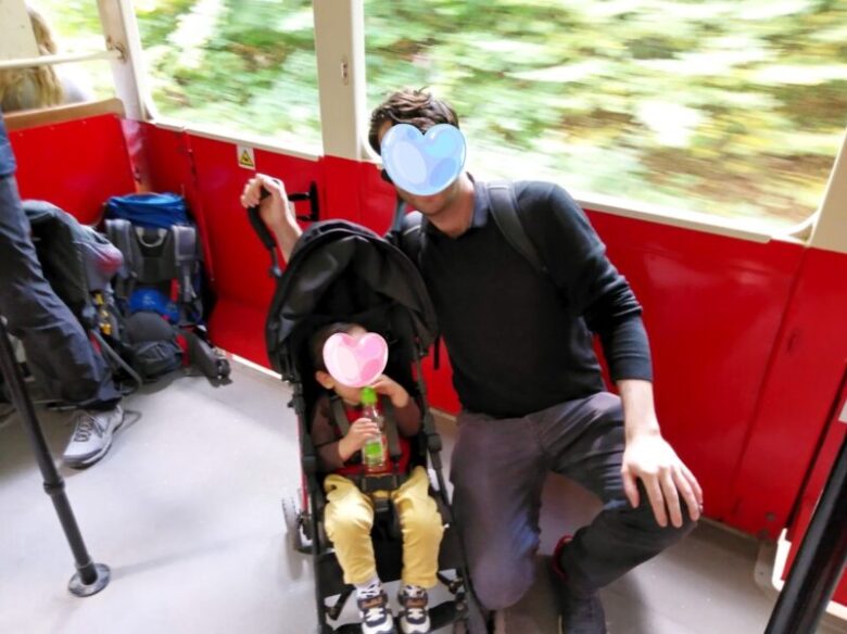 ブダペスト子供鉄道にベビーカーごと乗車し、子供車掌に写真を撮ってもらう親子