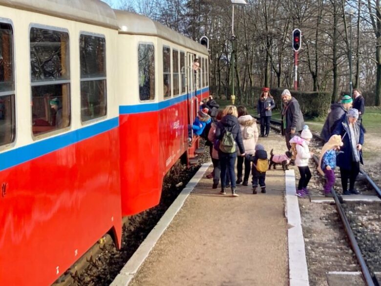 ブダペスト子供鉄道のSzépjuhászné駅で乗り降りする人々と子供鉄道員
