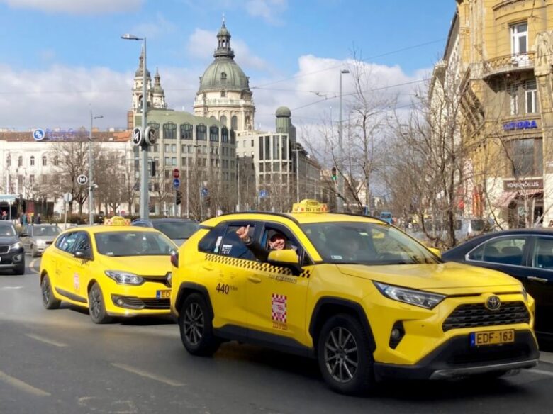 ブダペストの町の中で信号待ちをする2台のタクシー、Főtaxiのロゴがついている