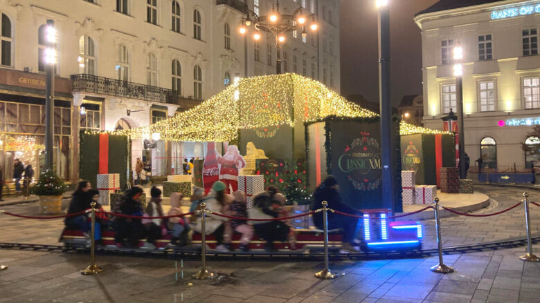 ブダペストのヴルシュマルティ広場のクリスマスマーケットでミニ列車を楽しむ人々