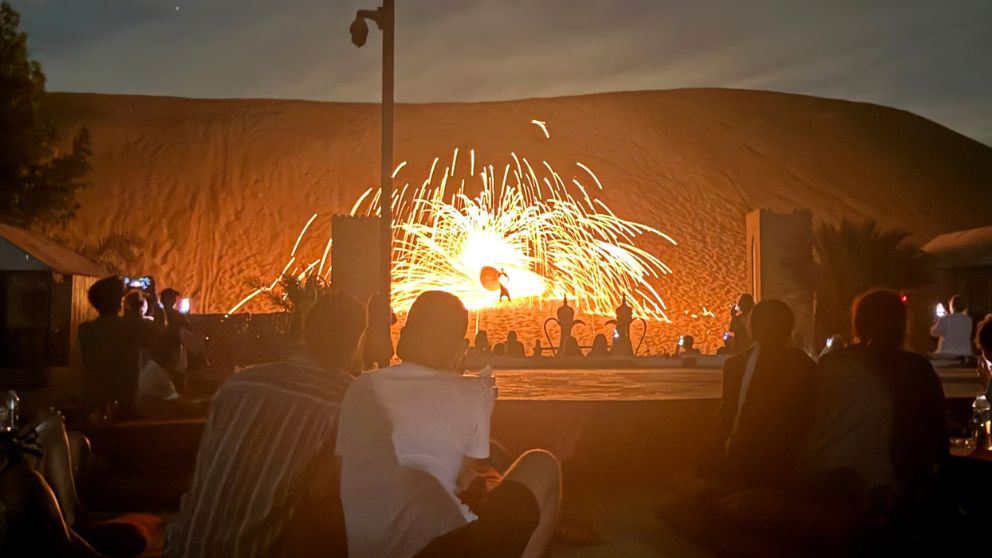 アブダビの砂漠ツアーのデザートキャンプで、砂丘へ上がってファイアーパフォーマンスをする男性