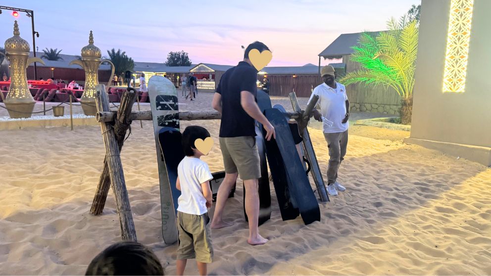 アブダビの砂漠ツアーのデザートキャンプで、サンドボードを選ぶ夫