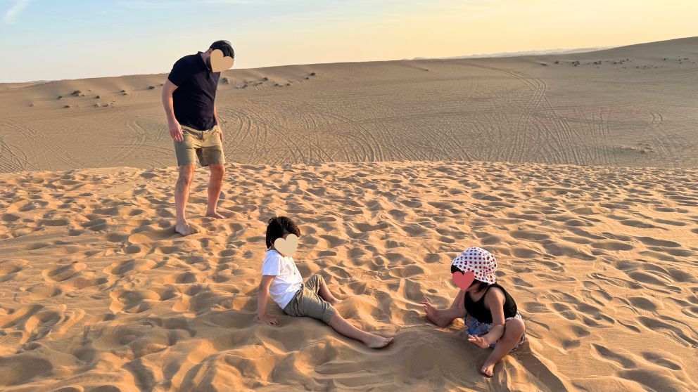 アブダビの砂漠ツアーのフォトストップで、砂遊びをする子どもたち