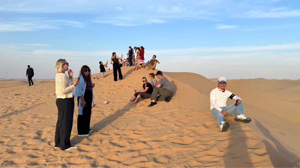 アブダビの砂漠ツアーのフォトストップで、思い思いに写真撮影をする観光客の様子