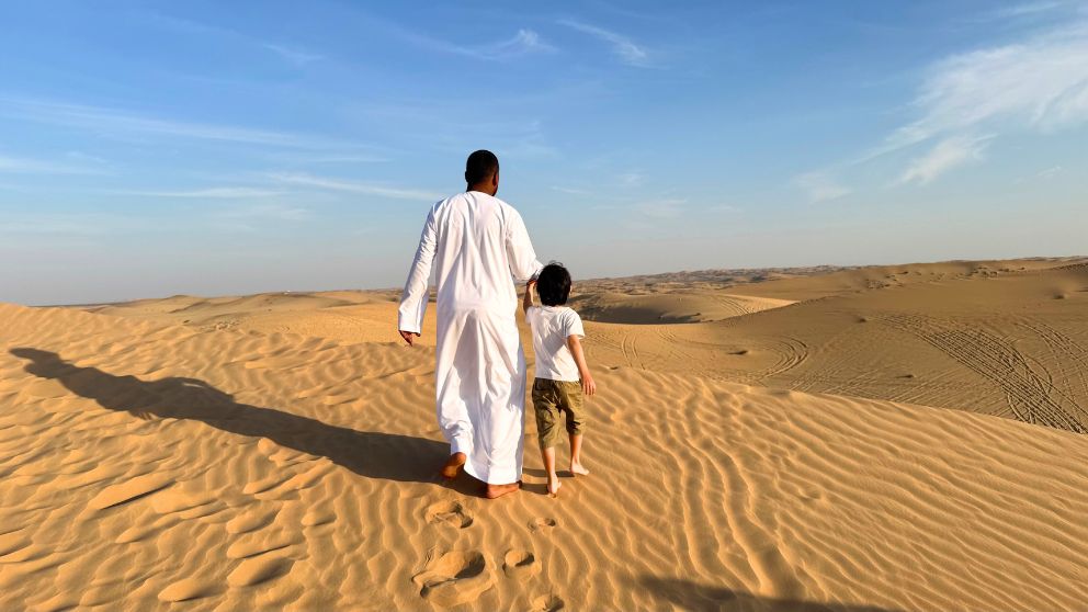 アブダビの砂漠ツアーのフォトストップで、運転手さんに連れられて砂丘を歩く息子