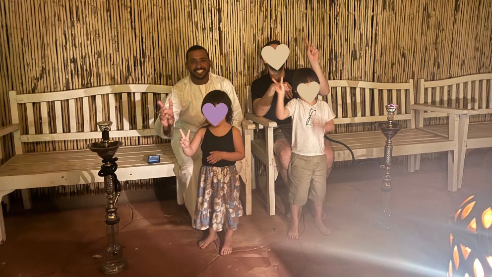 アブダビの砂漠ツアーのデザートキャンプで、シーシャ席に座って記念撮影をする私の家族と運転手さん