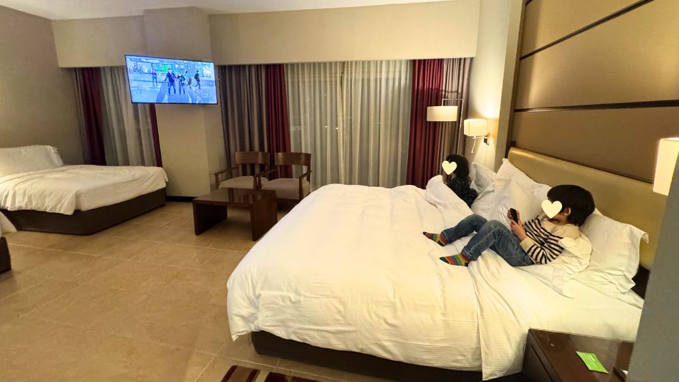 アブダビにあるホテルKhalidiya Palace Rayhaanのファミリールーム。ベッドに座る息子と娘