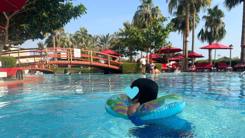 アブダビにあるホテルKhalidiya Palace Rayhaanのプールで、浮き輪につかまって泳ぐ息子