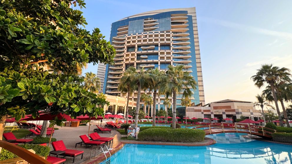 アブダビにあるホテルKhalidiya Palace Rayhaanのプールエリア。赤いパラソルとビーチチェアが印象的