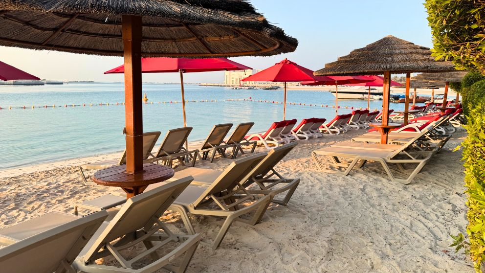 アブダビにあるホテルKhalidiya Palace Rayhaanのプライベートビーチに並ぶパラソルとビーチチェア