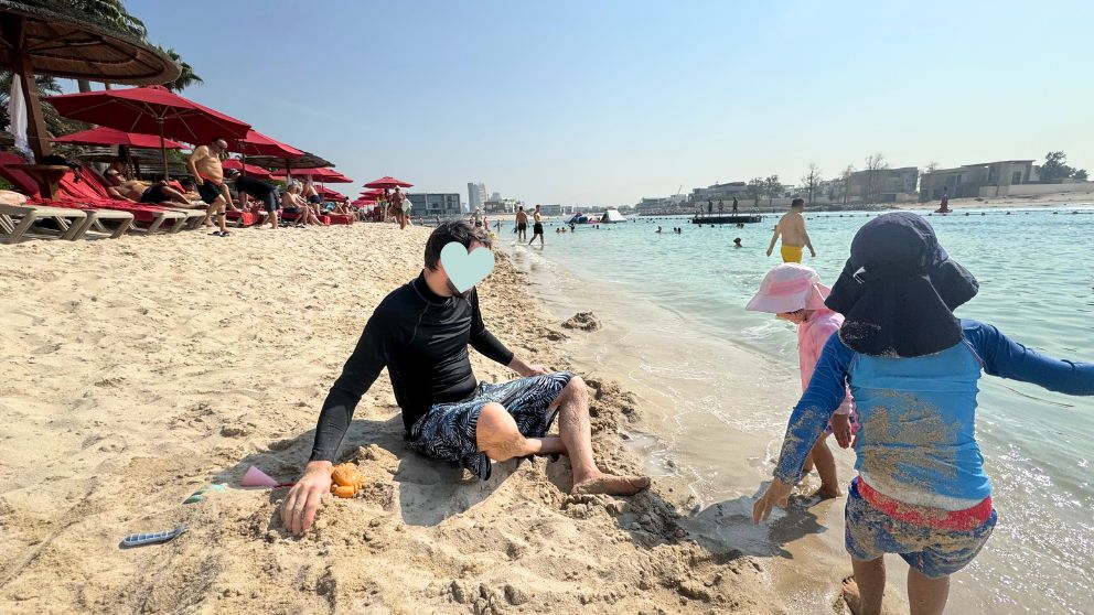 アブダビにあるホテルKhalidiya Palace Rayhaanのプライベートビーチで砂遊びをする家族