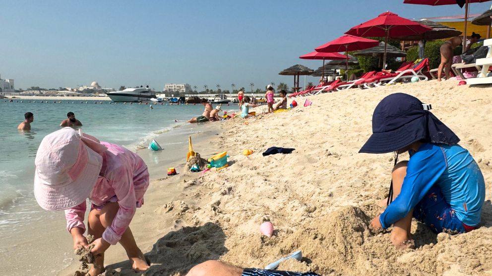 アブダビにあるホテルKhalidiya Palace Rayhaanのプライベートビーチで砂遊びをする息子と娘