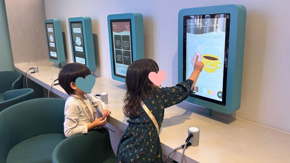 ハンガリー貨幣博物館のタッチパネル端末で、塗り絵を楽しむ娘とそれを眺める息子