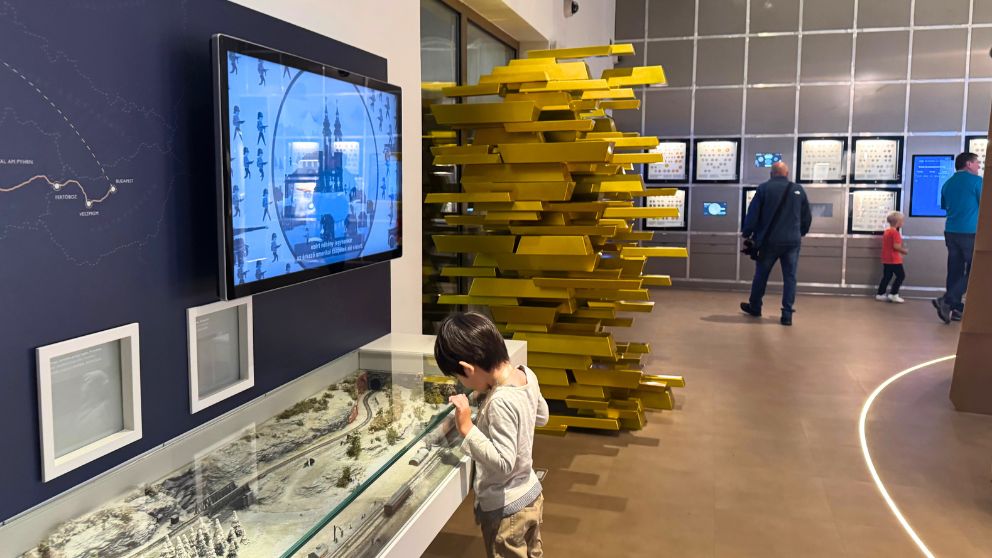ハンガリー貨幣博物館の地上階で、金色の列車のアート最後尾が飛び出した壁の様子