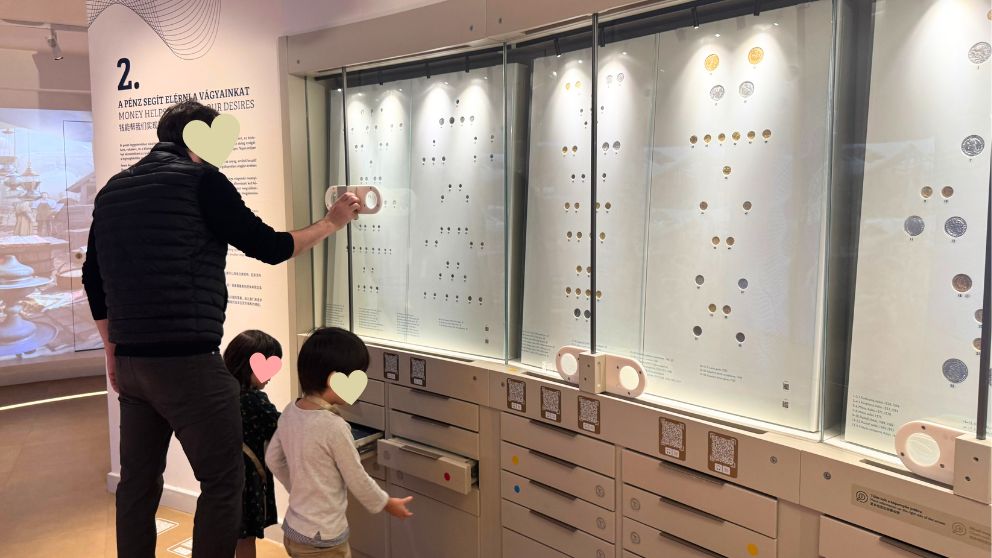 ハンガリー貨幣博物館のコインと紙幣のコレクションコーナーで、展示を眺める夫と子どもたちの様子