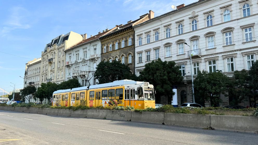 ブダペストのドナウ川沿いを走る黄色いトラム2番。ブダペストらしいエレガントな建物の前を走っている