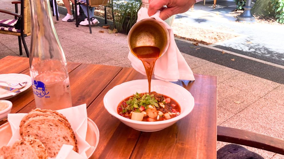 ブダペストの軍出るレストランのテラス席でサーブされたグヤーシュスープ