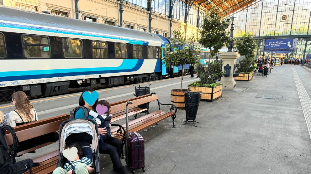 ブダペスト西駅のプラットホームでベンチに座る私と息子・娘。後ろにはハンガリー国鉄の列車が停車中