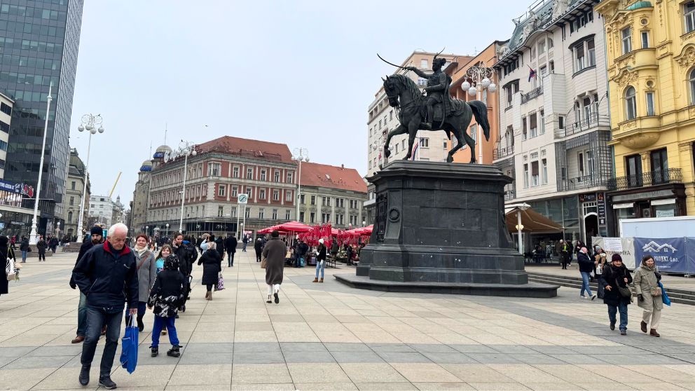 ザグレブのイェラチッチ広場の様子。奥には赤いパラソルがひらいていて、たくさんの人が歩いている
