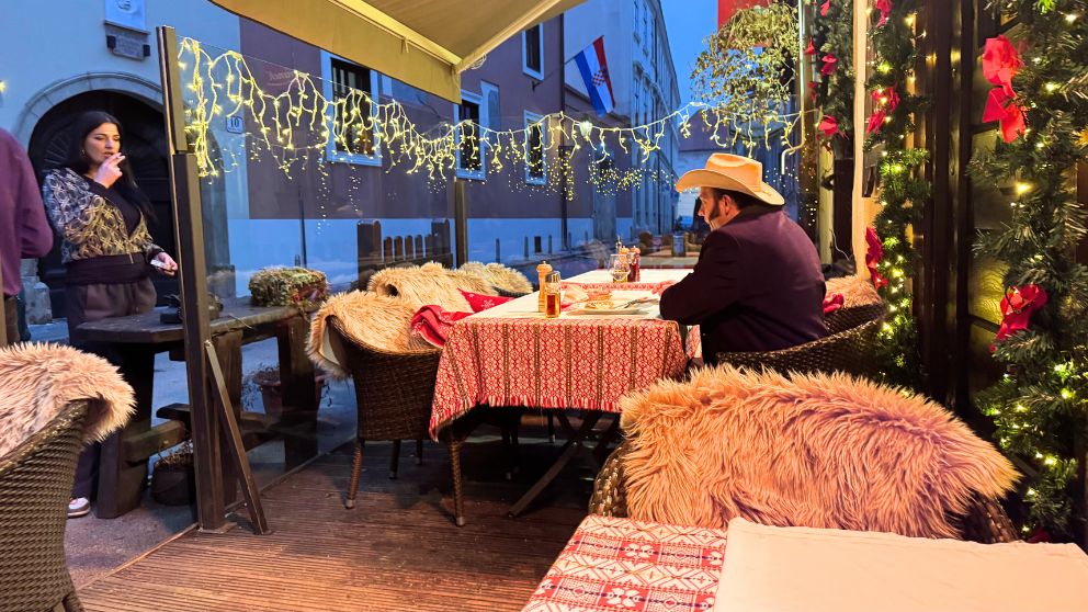 レストランのテラス席に座るお客さんと、外でタバコを吸う女性