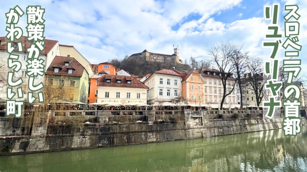 リュブリャナを流れるリュブリャニツァ川とそのほとりに並ぶ建物、背景の丘の上にはリュブリャナ城の景色