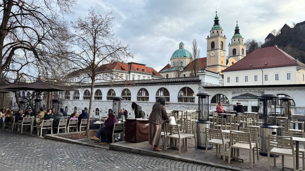 リュブリャナの中央市場や大聖堂が背景に見える川沿いのカフェの様子