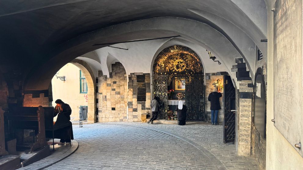 ザグレブ旧市街の石の門。聖母子画の前で熱心に祈りを捧げる人や、ろうそくに火を灯す人がいる様子