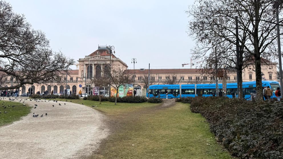 ザグレブ中央駅を公園から撮影。青いトラムが駅の前を走っている