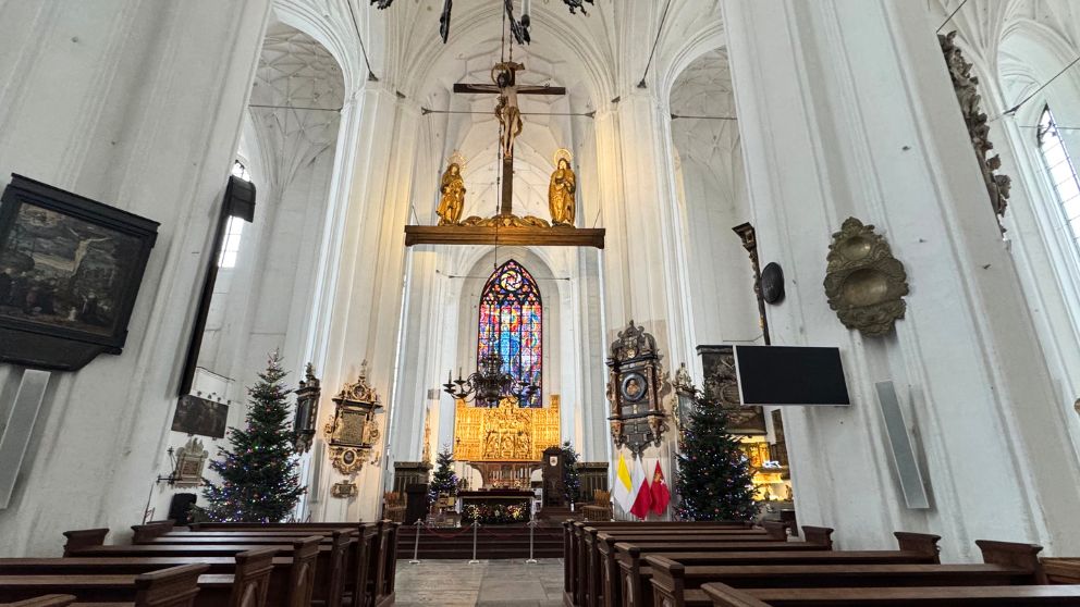 ポーランドのグダニスクにある聖マリア教会の内部の様子。白い壁で天井が非常に高く、奥正面のステンドグラスが美しい