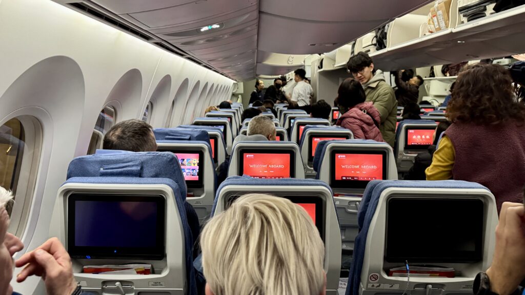 中国国際航空エコノミークラスの機内、搭乗中の乗客と「WELCOME ABOARD」と表示された赤いシートモニター