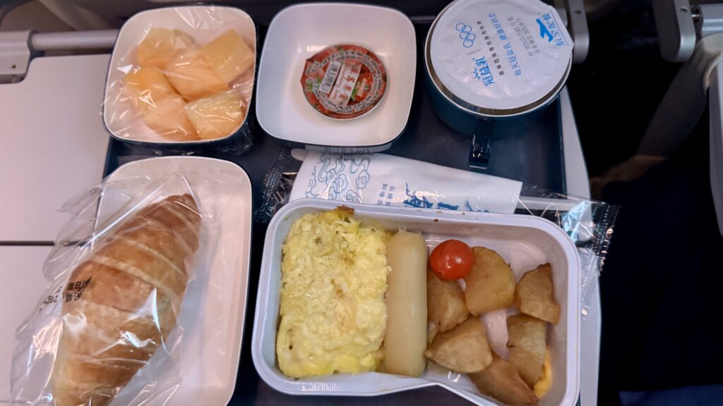 中国国際航空の機内朝食トレイ、スクランブルエッグ・ポテト・ミニトマト・クロワッサン・メロン