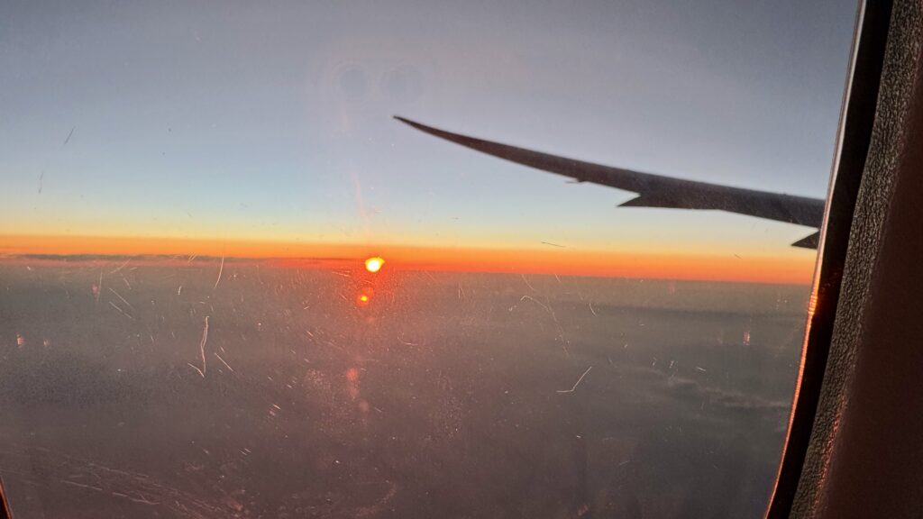 中国国際航空の機窓から見た夕焼け、翼のシルエットとオレンジ色に染まる地平線