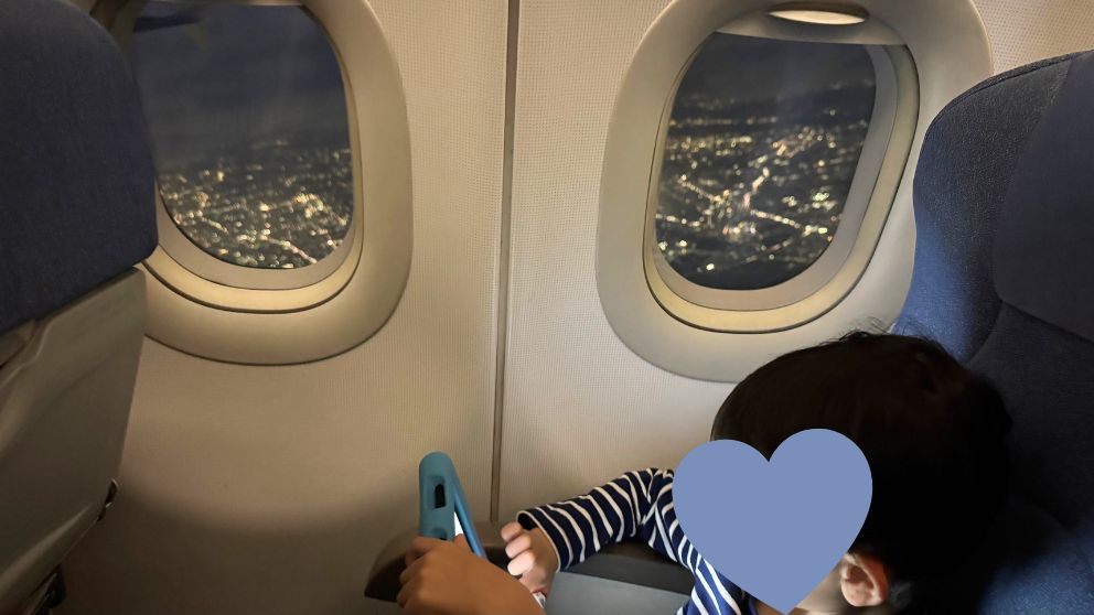中国国際航空の機内から見た夜景(羽田→北京)、座席にはタブレットをもった息子が座っている