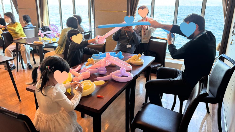 飛鳥Ⅱのコンパスルームで開催されたバルーンアート教室。窓の外には海が見え、机の上には家族で作ったバルーンアートが並んでいる