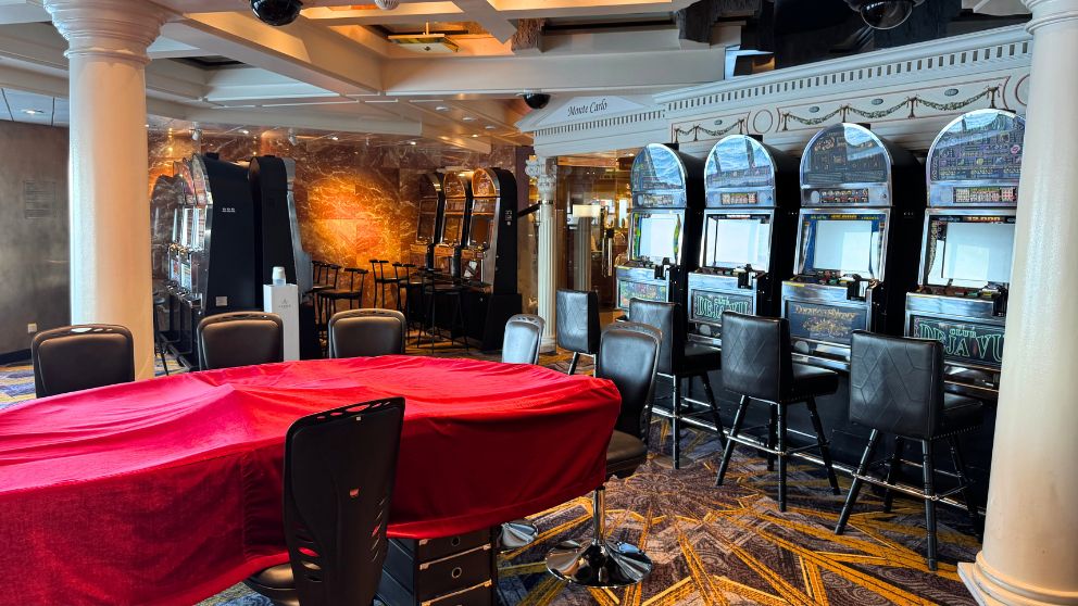 飛鳥Ⅱのカジノエリア『モンテカルロ』。赤いカバーがかかったゲームテーブルと、奥に並ぶスロットマシン