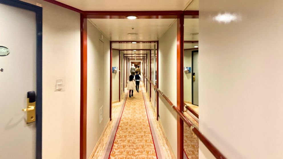 飛鳥Ⅱの7デッキの長い廊下を歩く息子と娘。長い廊下には絨毯が敷き詰められている