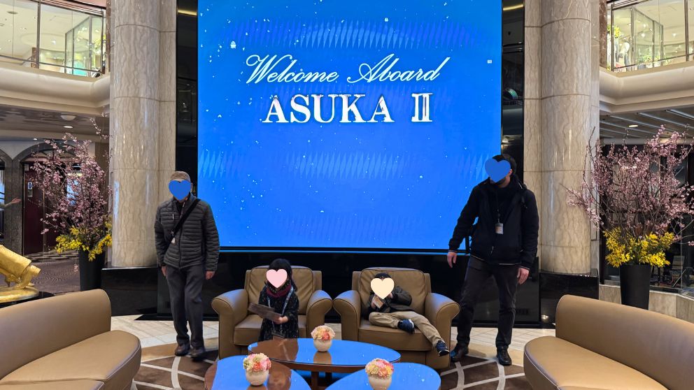 「Welcome to ASUKA CRUISE」と映し出されたスクリーンの前でくつろぐ私の家族