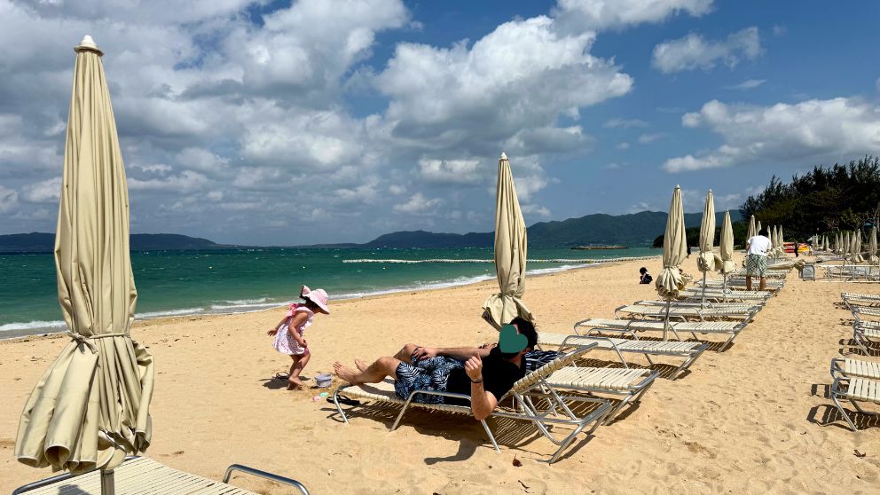 フサキビーチリゾートのビーチで砂遊びをする娘と、チェアに寝転がる夫