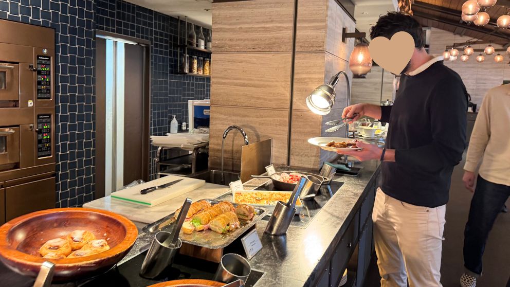 フサキビーチリゾートのIshigaki Bold Kitchenレストランで、朝食ビュッフェの食べ物をとる夫