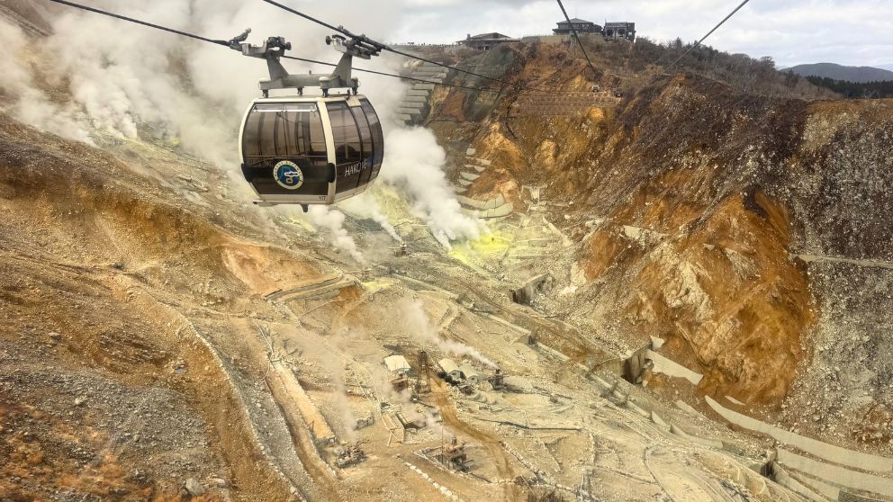 ロープウェイの窓から見下ろす、大涌谷の荒々しい岩肌と至る所から立ち上がる白い噴煙