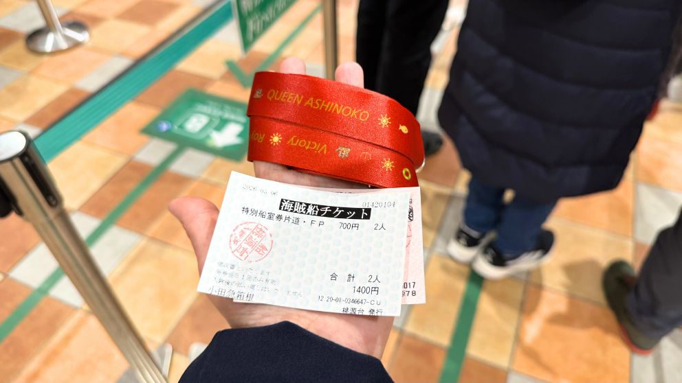 手のひらに乗せられた、箱根海賊船の乗船券2枚と「QUEEN ASHINOKO」と書かれた赤いリストバンド