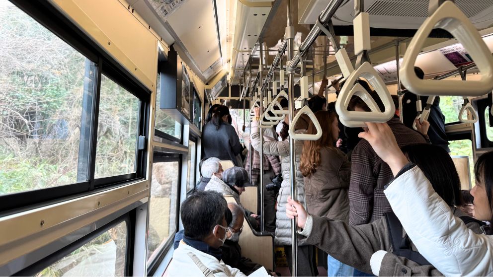 箱根登山ケーブルカーの車内。多くの乗客で賑わう様子と、車窓から見える急勾配の線路