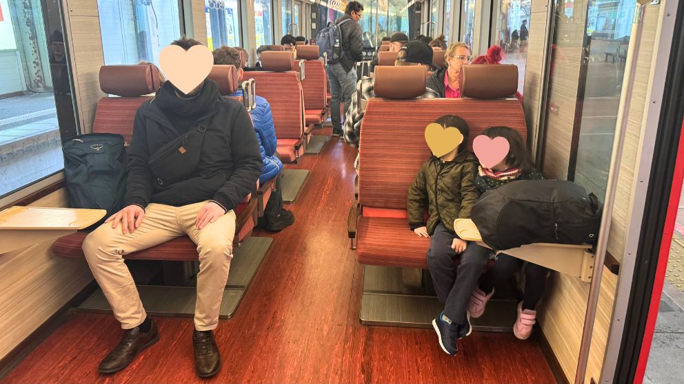 箱根登山電車のシートに並んで座る夫と子どもたち