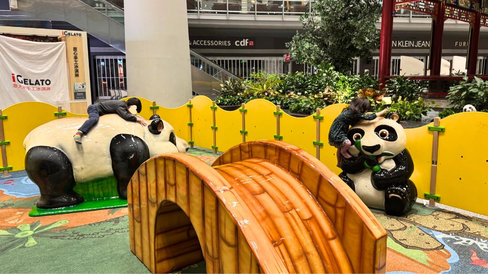 北京首都国際空港の遊び場でパンダの置物によじ登って遊ぶ子どもたち