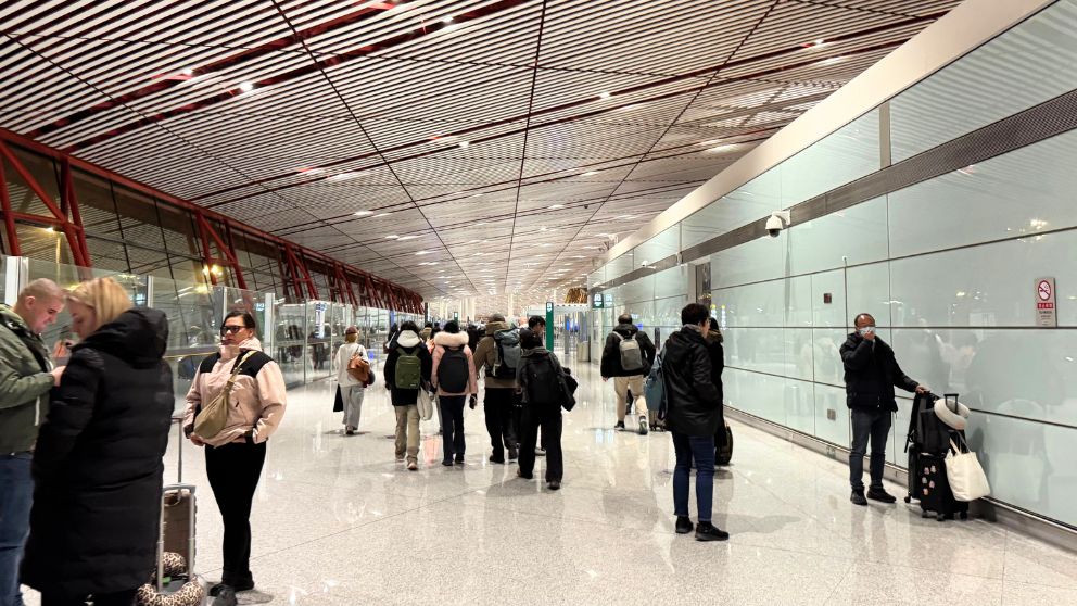 北京首都国際空港到着後、乗り継ぎ・出国エリアへ向かう旅行者たちが歩く通路