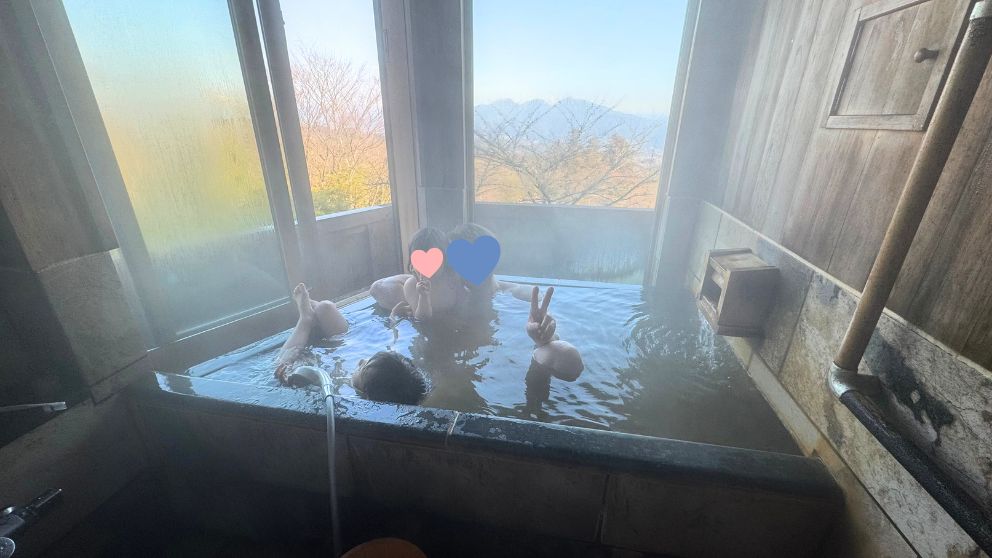 千明仁泉亭の客室露天風呂。山の景色を眺めながら家族で黄金の湯を楽しむ様子