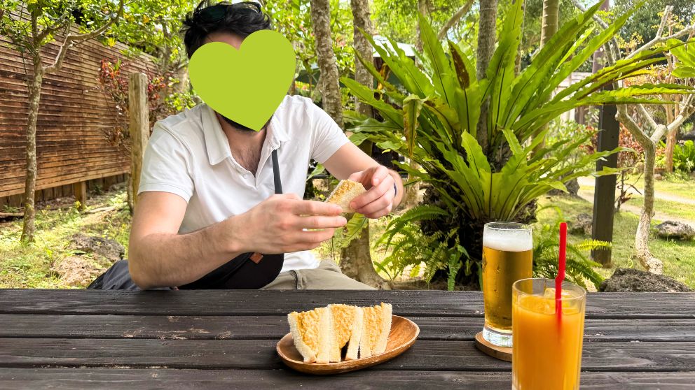 ちろりん村のテラス席で卵サンドを楽しむ様子。緑豊かな庭が広がる