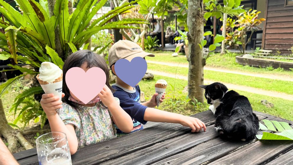 ろりん村でソフトクリームを手に持つ子どもたちと、テーブルに座る黒猫
