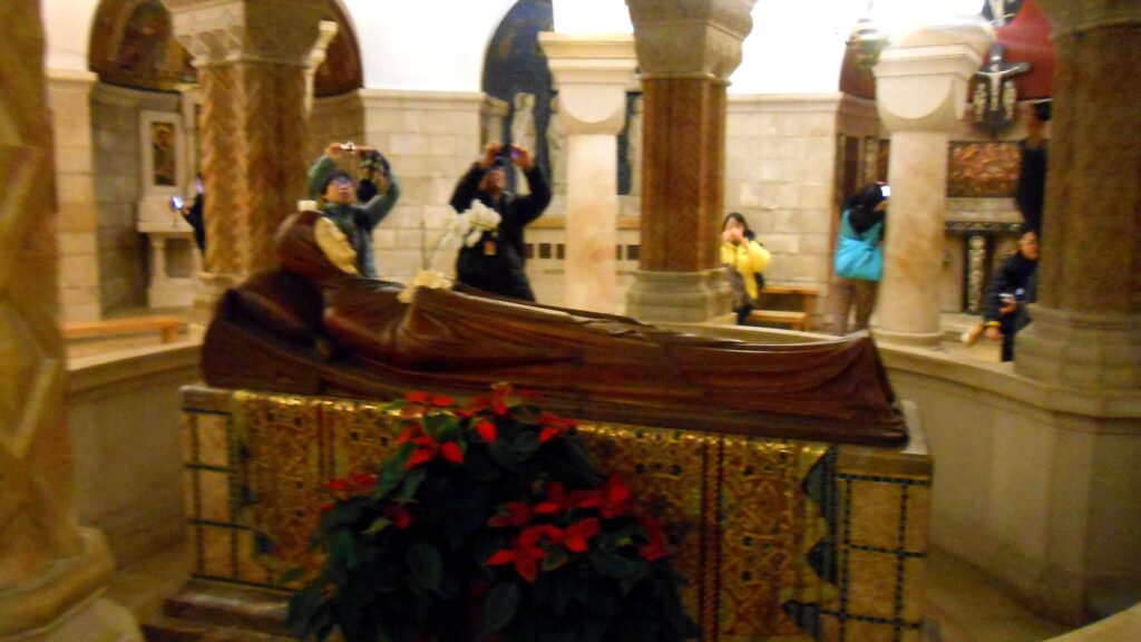 ドルミティオン大聖堂の地下聖堂。眠れる聖母マリアの像の周りで参拝者が写真を撮っている