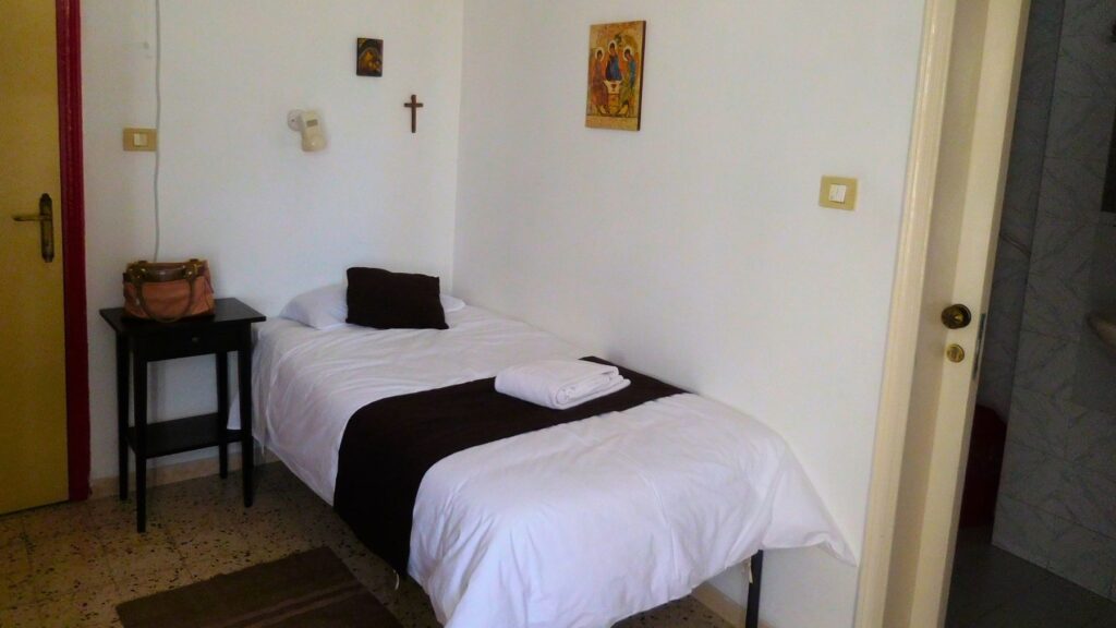 エッケホモ修道院のゲストハウスの部屋。シンプルなベッドとキリスト教の絵画が飾られた質素な空間